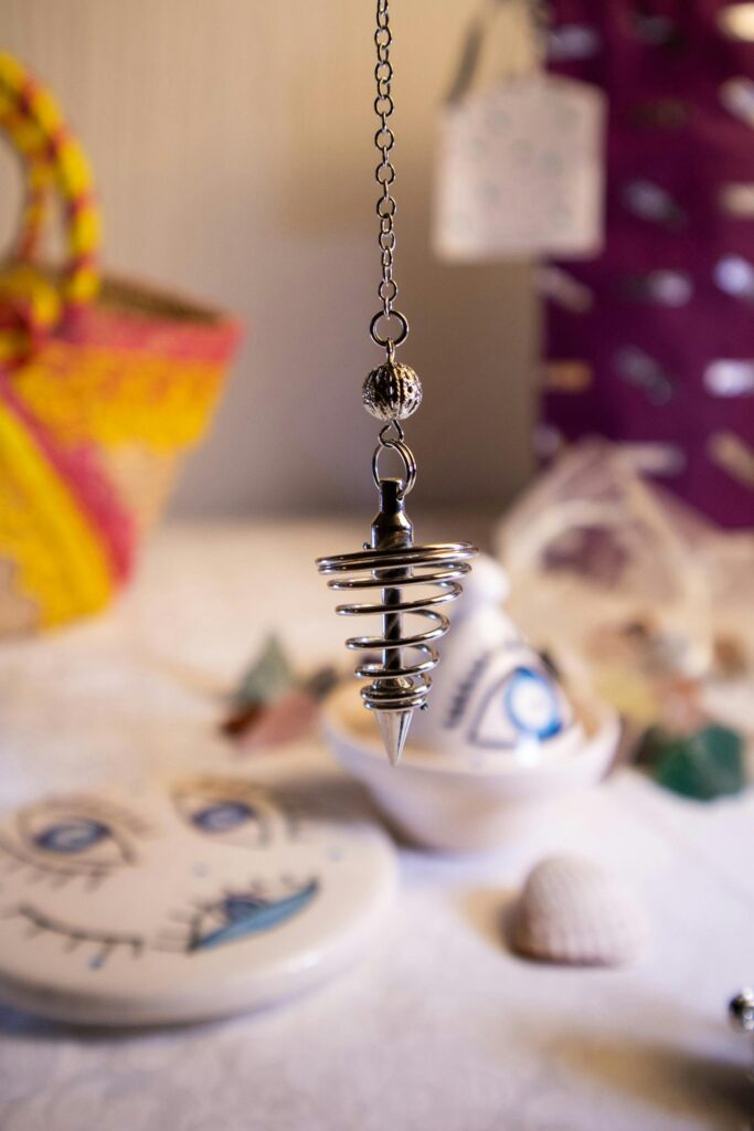 A silver pendulum hanging indoors among colorful cultural artifacts.